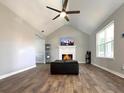 Bright living room featuring a vaulted ceiling, modern ceiling fan, and cozy fireplace with decorative mantel at 28 Fawn Ct, Sharpsburg, GA 30277