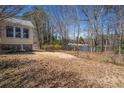 Backyard view of a home, featuring a spacious lawn and glimpses of a tranquil lake in the background at 3423 Conley Downs Drive, Powder Springs, GA 30127