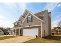 Side view of a two-story home with a large garage, well-maintained lawn, and a classic design at 1009 S Creek Dr, Villa Rica, GA 30180