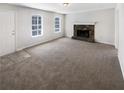 Spacious living room featuring a cozy stone fireplace, large windows, and neutral carpet at 405 Willow Shoals Dr, Covington, GA 30016