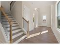 Bright foyer with hardwood floors, a staircase with modern railings, and a view of the entry door at 731 Crest Line W Trl, Powder Springs, GA 30127