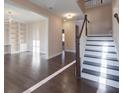 Bright living room featuring hardwood floors, elegant built-in shelves, and a staircase to the upper level at 6650 Canyon Cv, Cumming, GA 30028