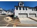 New construction townhome showcasing a two car garage with white brick exterior and paved driveway at 400 Renwood Trl, Johns Creek, GA 30097