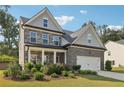 A cozy two-story house with a two-car garage, gray brick facade, and lush landscaping at 6235 Banyan Trl, Cumming, GA 30028