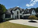 Elegant two-story home with black trim, circular driveway, and mature landscaping at 6045 Standard View Dr, Johns Creek, GA 30097