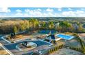 Aerial view showcasing community amenities: a pool, tennis courts, clubhouse, playground, and scenic surroundings for an active lifestyle at 1861 Lacebark Elm Way, Lawrenceville, GA 30045