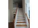 Wooden staircase featuring white railings and a view of the kitchen at 510 Pittman Mill Ct, Loganville, GA 30052