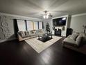 Comfortable living room featuring a large sectional sofa, fireplace, ceiling fan, and dark hardwood floors at 5215 Tye Trl, Fairburn, GA 30213