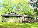 Back exterior of home with an expansive lawn, stone chimney, and wooden deck at 1312 La Mesa Dr, Lawrenceville, GA 30043
