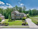 Aerial view of a beautiful home with lush greenery, a long driveway, and manicured landscaping at 4590 Gablestone Xing, Hoschton, GA 30548