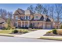 Gorgeous two-story brick home with an attached two-car garage, beautifully landscaped yard, and inviting front porch at 4590 Gablestone Xing, Hoschton, GA 30548