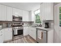 Bright kitchen features white cabinets, stainless steel appliances, and light countertops at 1056 Ferry Creek Way, Acworth, GA 30102