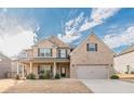 Lovely two-story brick home showcasing a covered front porch and a spacious two-car garage at 879 Tranquil Way, Hampton, GA 30228