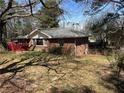 View of the back of a brick home showcasing an open yard with mature trees at 496 Elizabeth Sw Ln, Mableton, GA 30126