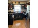 Functional kitchen features wood cabinets, laminate counters, black appliances and wood floors at 496 Elizabeth Sw Ln, Mableton, GA 30126