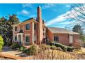 Rear view showcasing the brick architecture, large windows, and landscaped yard with mature trees at 3832 Wesley Chapel Rd, Marietta, GA 30062