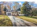 A long concrete driveway leads to this charming home featuring lovely fall foliage and a well-kept lawn at 1697 Dyson Ne Dr, Atlanta, GA 30307