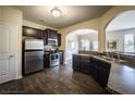 Well-lit kitchen featuring dark cabinetry, stainless steel appliances, granite counters, and a view of the dining area at 326 Lauren Dr, Fairburn, GA 30213