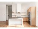 Modern kitchen featuring a large island, stainless steel appliances, light wood cabinets, and natural light at 1235 Lupo Loop, Palmetto, GA 30268