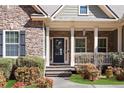 Inviting front porch entrance featuring stone accents, columns, and a decorative front door at 1656 Maes Overlook, Loganville, GA 30052