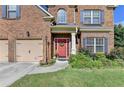 Close-up view of a two-story brick home's front door, attached garage, and landscaped front yard at 1211 Chapel Estates Way, Dacula, GA 30019