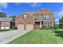 Inviting two-story brick home featuring a red front door, attached two-car garage and well-maintained lawn at 1211 Chapel Estates Way, Dacula, GA 30019