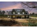 Charming two-story home with a covered porch, green siding, and a welcoming red front door at dusk at 529 Claude Scott Rd, Canton, GA 30115
