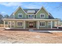 Inviting two-story home boasts a covered front porch, green siding, and white trim details under a bright blue sky at 529 Claude Scott Rd, Canton, GA 30115