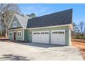 Side view showcases a three-car garage with white doors, green siding, and a concrete driveway leading to the house at 529 Claude Scott Rd, Canton, GA 30115