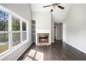 Cozy living room with hardwood floors, vaulted ceiling, a stone fireplace, and ample natural light from a large window at 221 Makayla Way, Temple, GA 30179