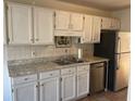 Bright kitchen featuring white cabinets, stainless steel appliances, neutral countertops, and tile backsplash at 5012 Jenny Dr, Acworth, GA 30101