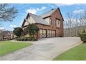 Rear exterior view of a brick home with a two-car garage and a long driveway in a landscaped yard at 3060 Salisbury Ln, Cumming, GA 30041
