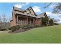 Inviting front of home with a blend of brick and stone, a covered porch and lush, green landscaping at 3060 Salisbury Ln, Cumming, GA 30041