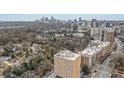 This aerial view captures the building and the neighborhood with city views and ample trees at 2285 Peachtree Ne Rd # 1107, Atlanta, GA 30309