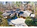 Aerial view of a beautiful home with stone accents, a turret, and a brick driveway surrounded by greenery at 4421 Paradise Cir, Vinings, GA 30339