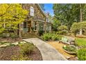 Charming stone facade with a welcoming walkway leading to a quaint front porch, bench seating, and lush landscaping at 1993 Mount Vernon Pl, Dunwoody, GA 30338
