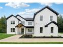 A beautiful two-story white brick home featuring black trim, black roof and lush landscaping at 3165 Hall Rd, Dacula, GA 30019