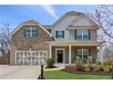 Beautiful two-story home boasting a brick facade, inviting front porch, and meticulously landscaped front yard at 6350 Boulder Rdg, Cumming, GA 30028