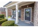 Welcoming front porch with stone accents, a seating area, and a beautifully decorated front door with sidelight at 4162 Roberts Crest Dr, Suwanee, GA 30024