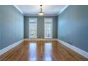 Empty room featuring hardwood floors, pale blue walls, white trim, and abundant natural light from two windows at 12 Candler Grove Dr, Decatur, GA 30030
