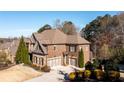 Beautiful brick home with a two-car garage, mature trees and well-manicured landscaping and driveway at 5230 Harris Springs Dr, Cumming, GA 30040