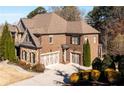 Beautiful brick home with a three-car garage, lush landscaping, and a neatly paved driveway at 5230 Harris Springs Dr, Cumming, GA 30040
