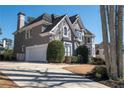 Side view of a gray two-story home with a two-car garage and manicured landscaping at 6305 Deerwoods Trl, Alpharetta, GA 30005