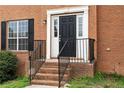Close-up of a home's front door entrance and steps with a black handrail and brick facade at 2557 Tolliver Dr, Ellenwood, GA 30294