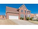 View of a brick home with a large front lawn and attached two-car garage on a sunny day at 5594 Mountain View Pass, Stone Mountain, GA 30087