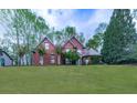 Lovely brick home with a lush green lawn and mature trees surrounding the property at 3280 Peace Ln, Suwanee, GA 30024