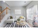 Bright living room featuring a staircase, white couch, striped rug, and natural light from the large window at 5729 Newnan Cir, Austell, GA 30106