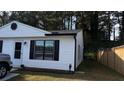 A house featuring white siding and black window trim, complemented by a well-kept lawn and a wooden fence at 4778 Pebble Trce, Buford, GA 30518