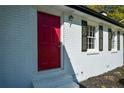 Close-up of a painted white brick home featuring a bright red front door and black shutters at 2157 Tiffany Ln, Lithonia, GA 30058