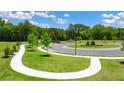 Beautiful community entrance with sidewalks lining the roadway and manicured green spaces with trees at 8599 Secretariat Dr, Lithonia, GA 30058